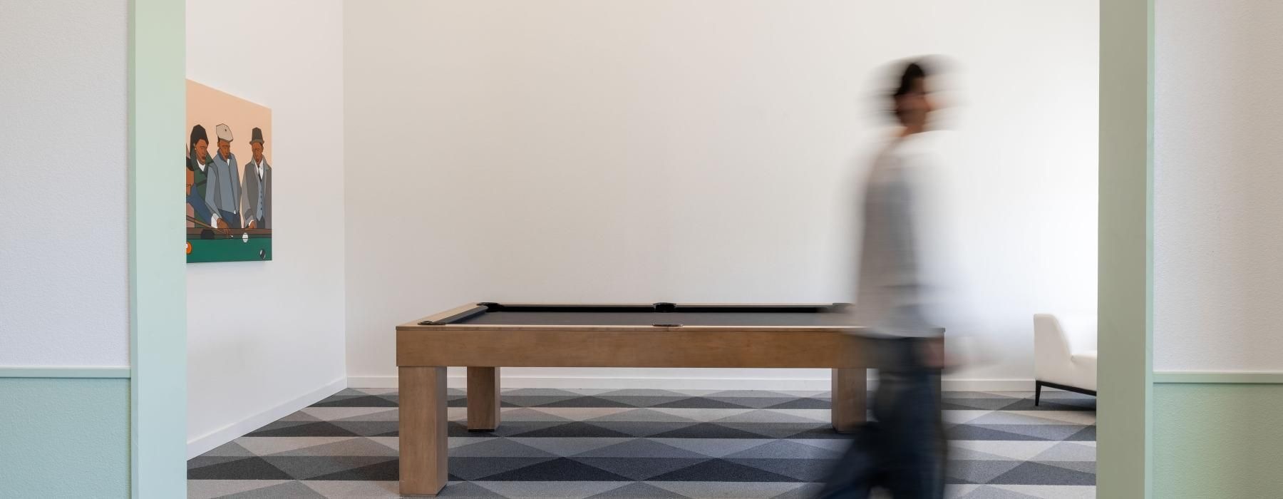 a person walking in a room with a pool table